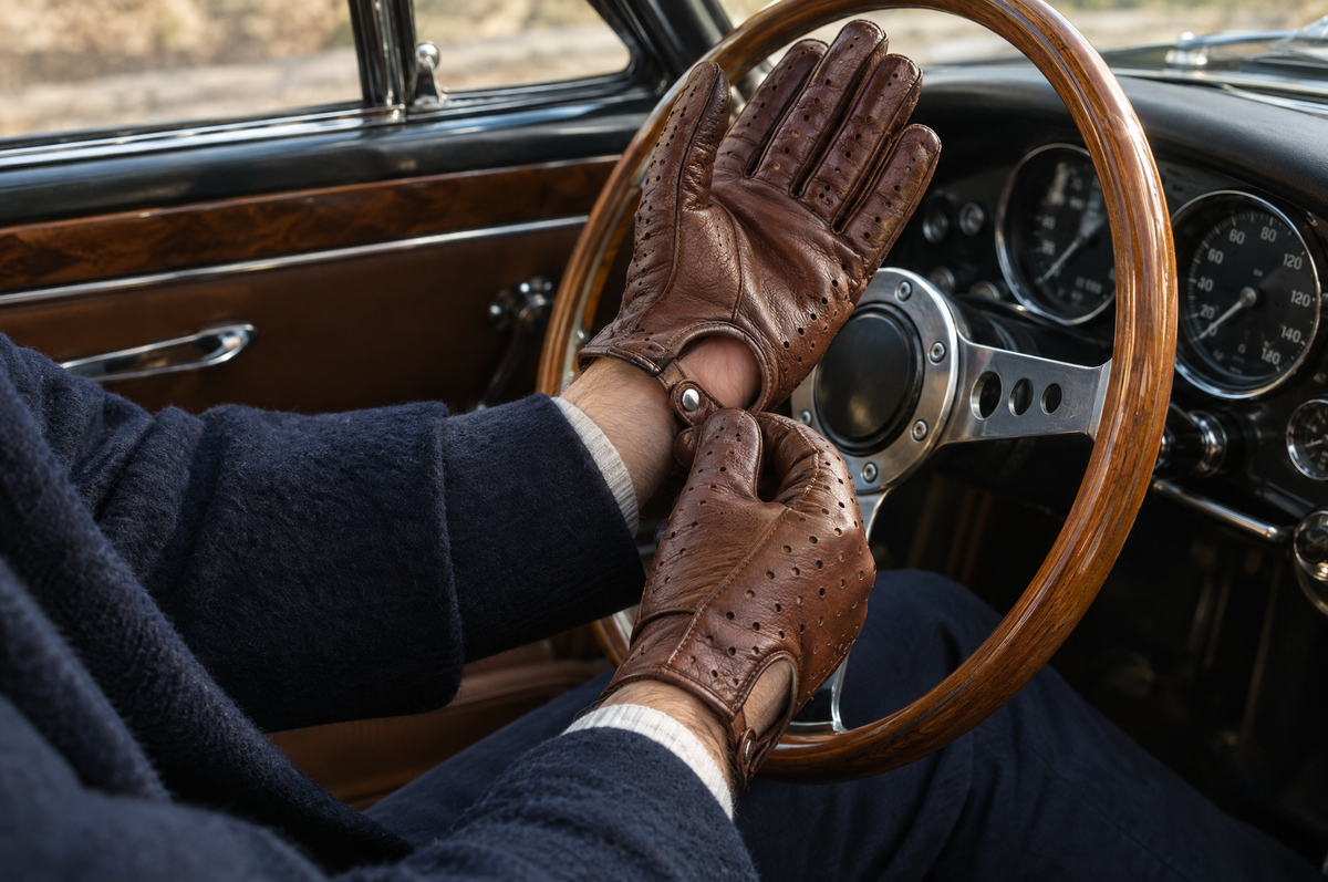 Homme enfilant des gants de conduite en cuir perforé au volant d'une voiture ancienne Image